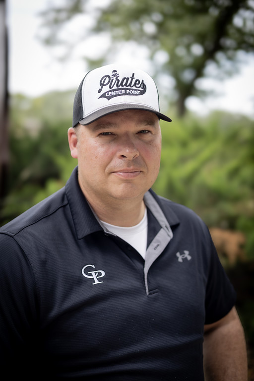 A person wearing a white and black baseball cap with 'Pirates' and a dark polo shirt with 'GP' stands outdoors.